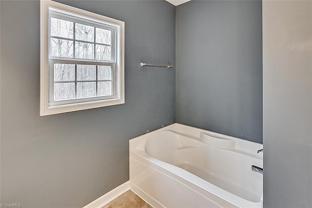 bathroom with a garden tub, baseboards, and tile patterned floors