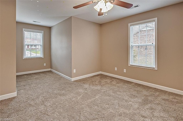 carpeted empty room featuring visible vents, ceiling fan, and baseboards