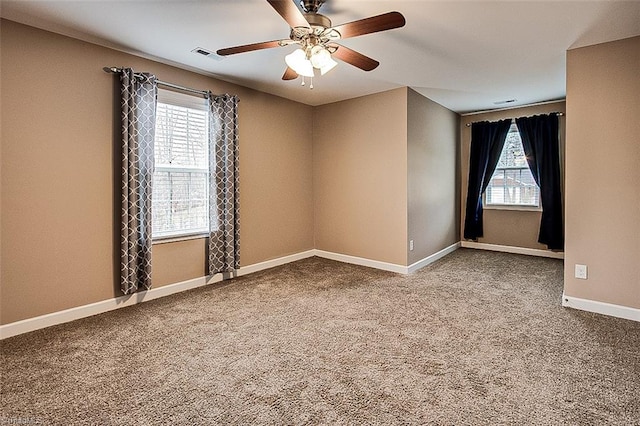 carpeted empty room featuring baseboards, visible vents, a wealth of natural light, and ceiling fan