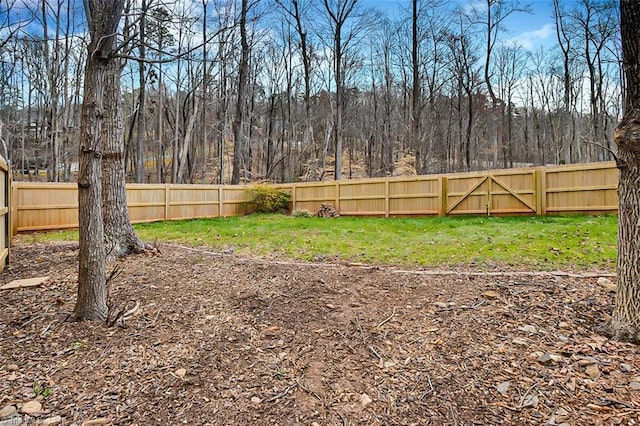 view of yard with a fenced backyard and a view of trees