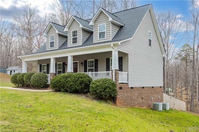 cape cod home with covered porch, a shingled roof, and a front lawn