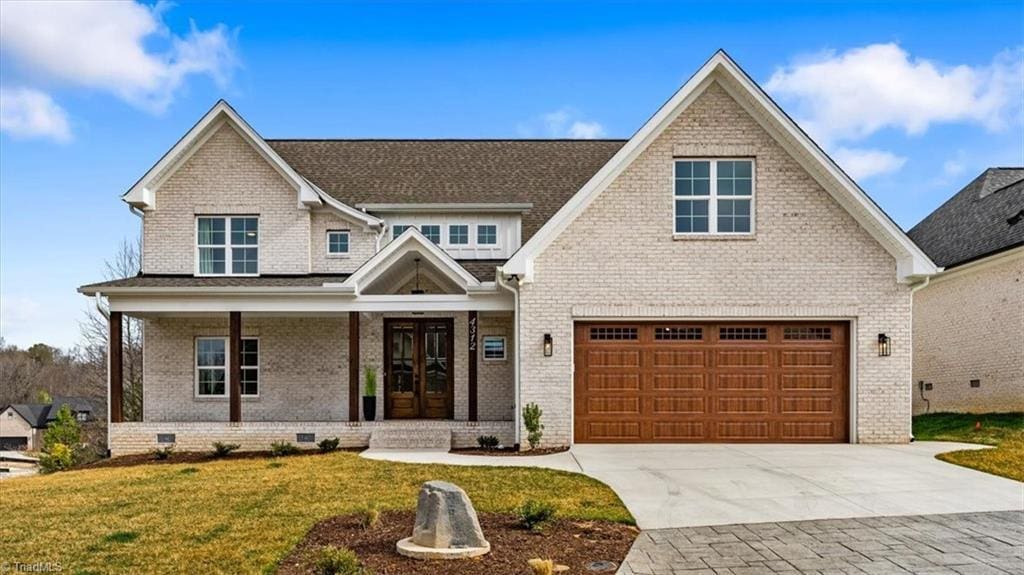 4312 Griffins Gate Ln, Greensboro, NC 27407 - view of front of house featuring french doors, driveway, a front yard, covered porch, and brick siding