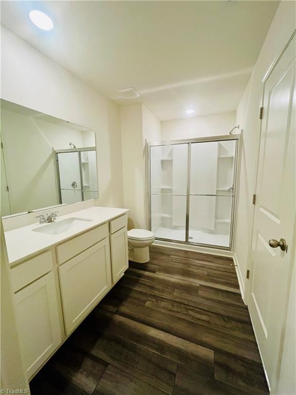 full bathroom featuring toilet, wood finished floors, vanity, recessed lighting, and a stall shower