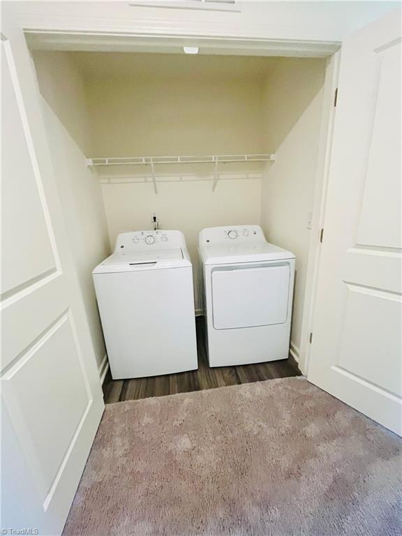 laundry room featuring dark wood finished floors, laundry area, and washer and clothes dryer