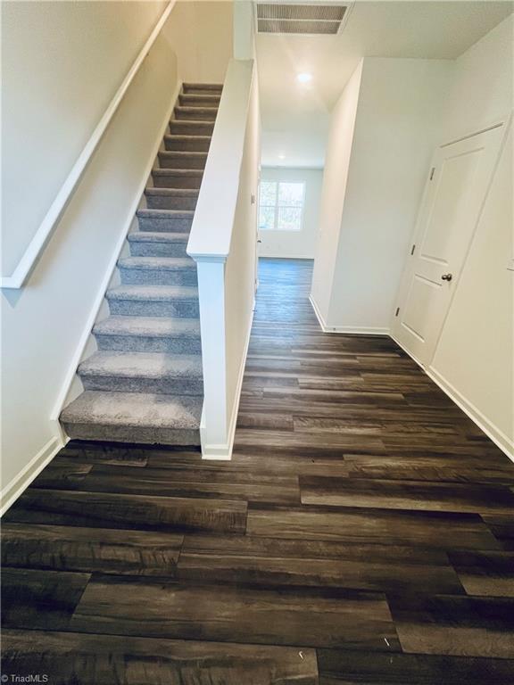 stairs with visible vents, wood finished floors, and baseboards