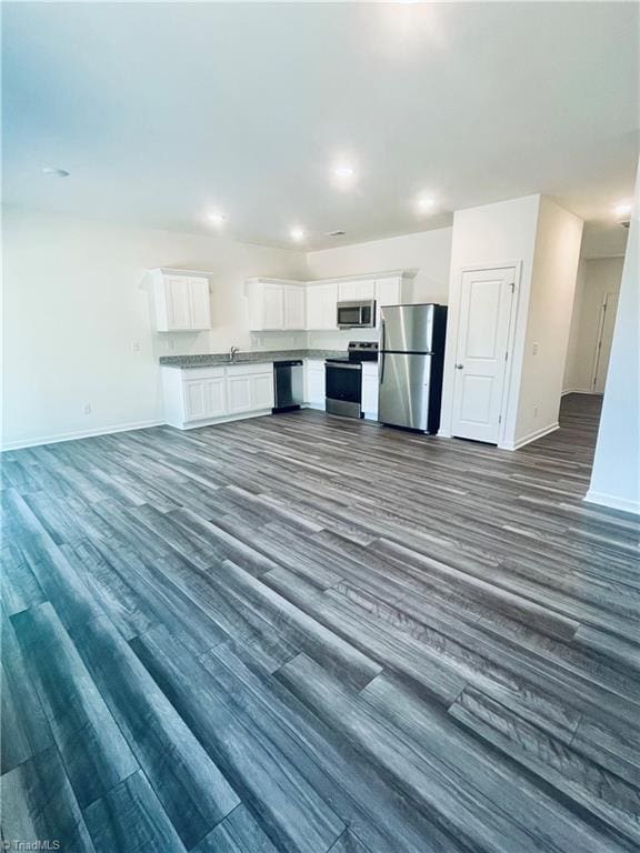 kitchen with baseboards, dark wood-style flooring, open floor plan, and appliances with stainless steel finishes