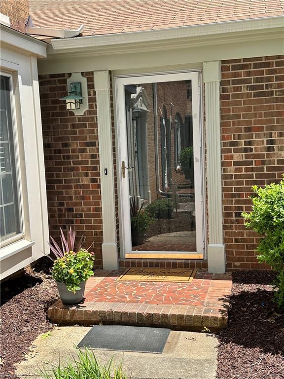 4814 Tower Rd, Greensboro, NC 27410 - view of exterior entry featuring brick siding and roof with shingles