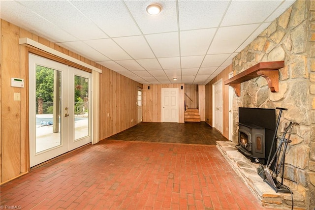 657 Spring St, Walnut Cove, NC 27052 - unfurnished living room with brick floors, wood walls, stairs, a wood stove, and french doors