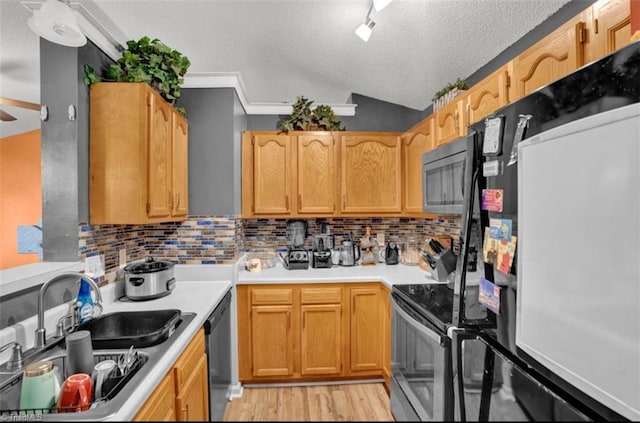 kitchen with a textured ceiling, backsplash, stainless steel appliances, and sink