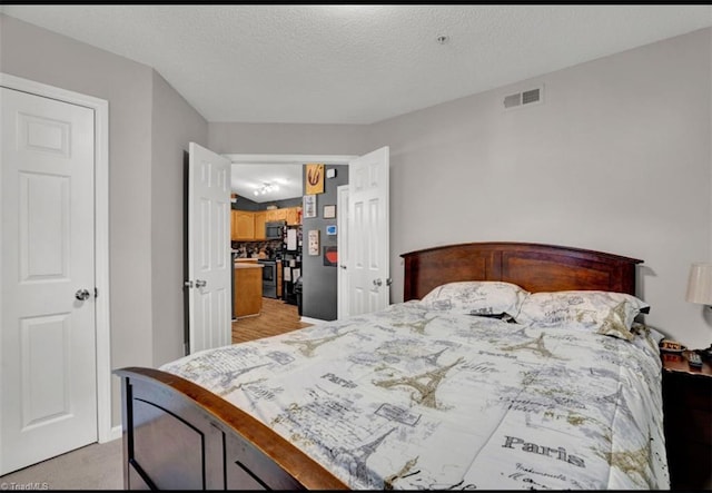 bedroom with light colored carpet and a textured ceiling