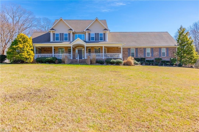 view of front of property featuring a porch, brick siding, and a front lawn