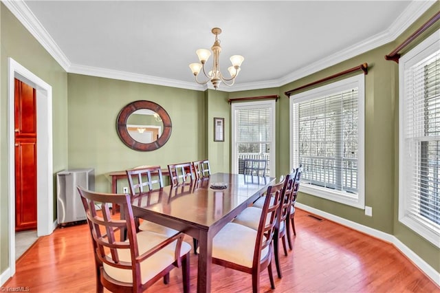 dining space with a chandelier, light wood finished floors, ornamental molding, and baseboards