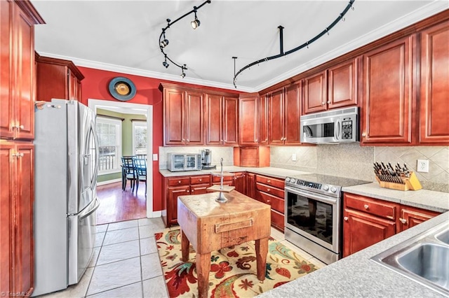 kitchen with stainless steel appliances, light countertops, decorative backsplash, a sink, and dark brown cabinets