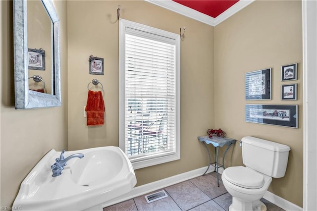 half bath with visible vents, toilet, a sink, tile patterned flooring, and baseboards