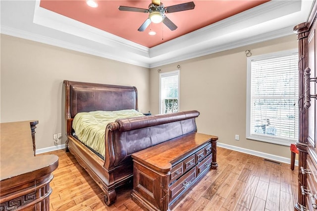 bedroom featuring a tray ceiling, baseboards, and light wood finished floors