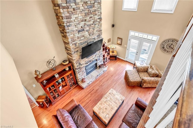 living area with french doors, a healthy amount of sunlight, a fireplace, and wood finished floors