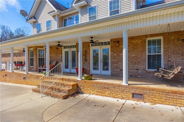 doorway to property featuring brick siding, ceiling fan, a patio, and french doors