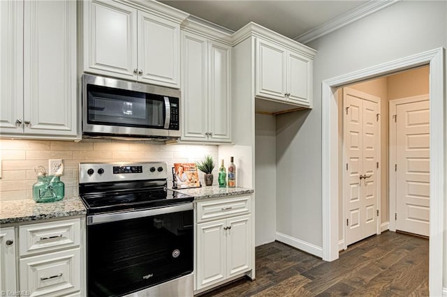 kitchen with light stone counters, white cabinets, appliances with stainless steel finishes, dark hardwood / wood-style flooring, and ornamental molding