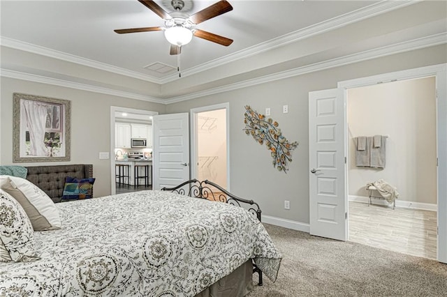 bedroom with ceiling fan, ornamental molding, carpet, and a walk in closet