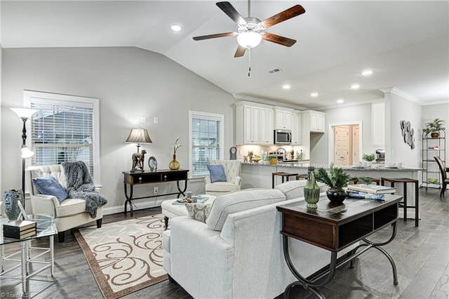 living room with lofted ceiling, ornamental molding, ceiling fan, and dark wood-type flooring