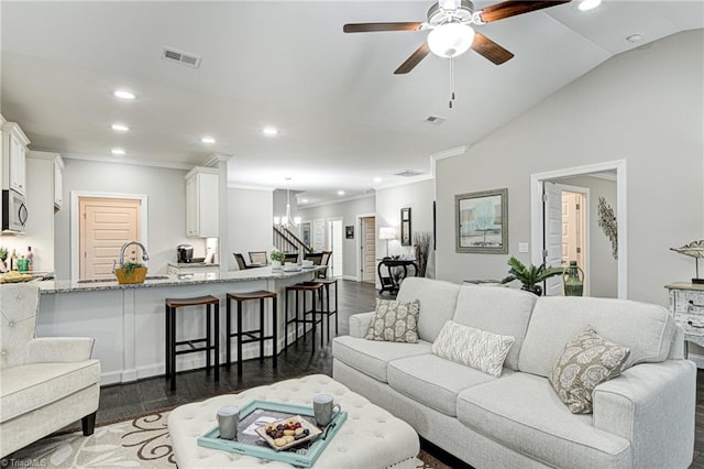 living room featuring ceiling fan with notable chandelier, lofted ceiling, crown molding, and dark hardwood / wood-style flooring