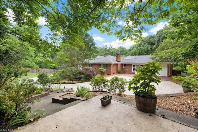 252 Lucerne Ln NW, Winston-Salem, NC 27104 - view of patio featuring a garage, driveway, and a garden