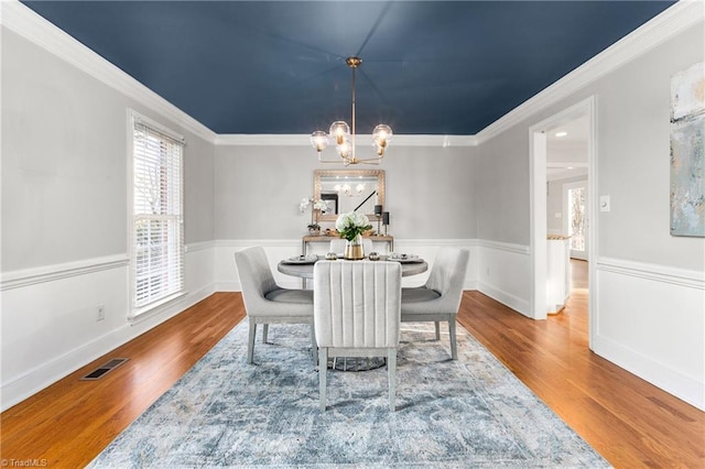 dining room featuring crown molding, wood-type flooring, and an inviting chandelier