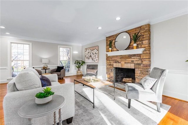 living room featuring crown molding, a fireplace, and light wood-type flooring