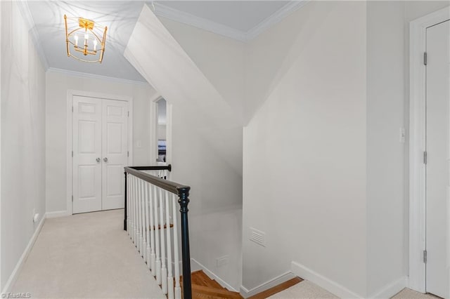 hallway with a notable chandelier, ornamental molding, and light carpet