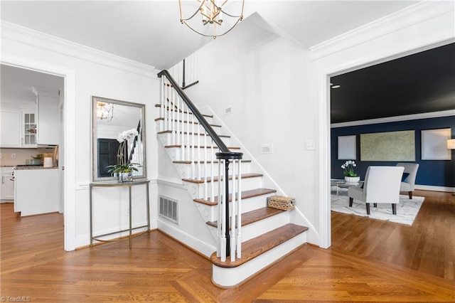 stairway featuring parquet floors, a chandelier, and ornamental molding