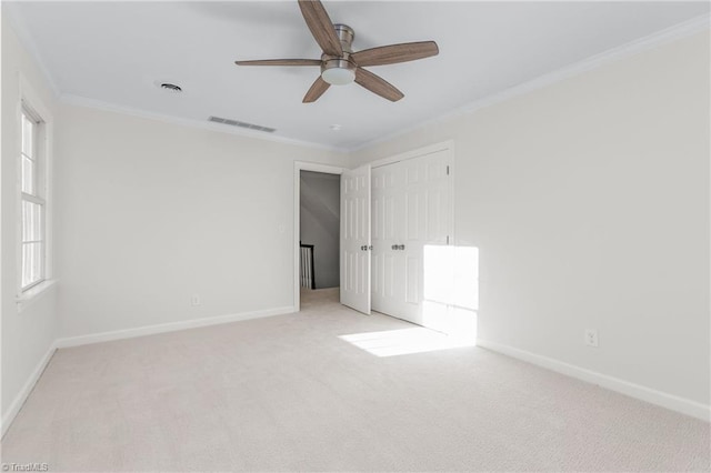 spare room featuring ceiling fan, light colored carpet, and crown molding