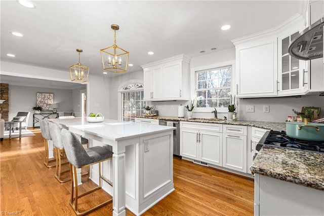 kitchen with white cabinets, a kitchen island, light hardwood / wood-style floors, and hanging light fixtures