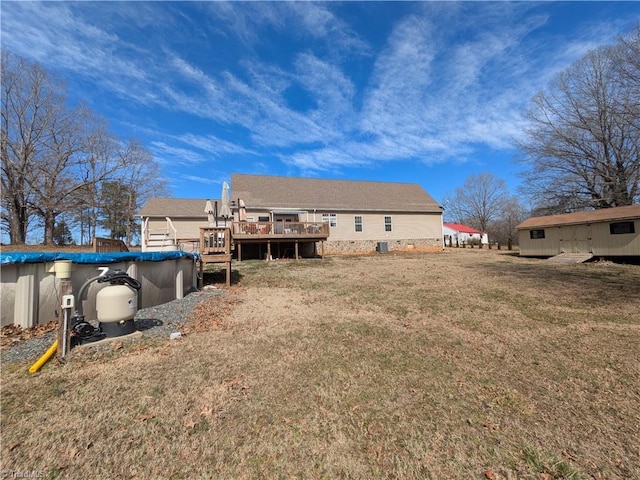 rear view of house featuring a covered pool, a yard, and a deck