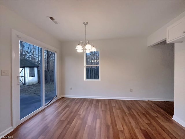 unfurnished dining area with a notable chandelier, plenty of natural light, and wood-type flooring