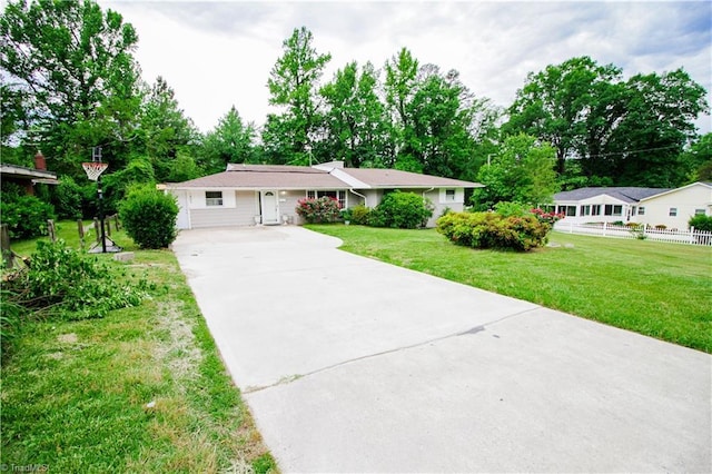 ranch-style home with concrete driveway and view of scattered trees
