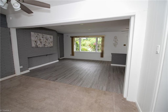unfurnished living room featuring baseboards, ceiling fan, wood finished floors, and a large fireplace