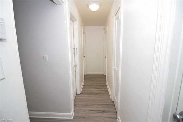 hallway featuring light wood finished floors and baseboards