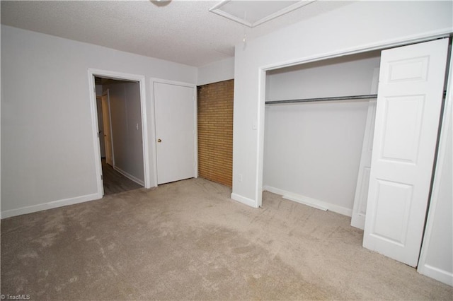 unfurnished bedroom featuring carpet, attic access, a textured ceiling, and baseboards