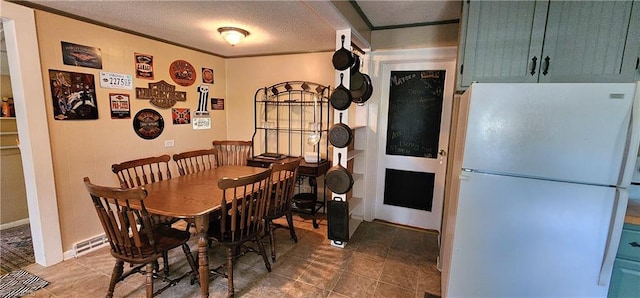 dining space with a baseboard radiator, a textured ceiling, and crown molding