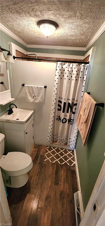 bathroom with wood-type flooring, vanity, a shower with curtain, toilet, and crown molding