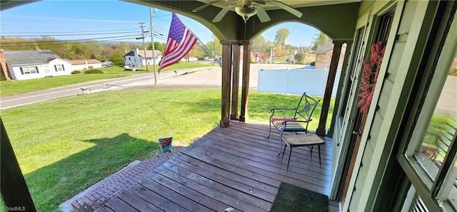 wooden deck featuring ceiling fan, a porch, and a yard