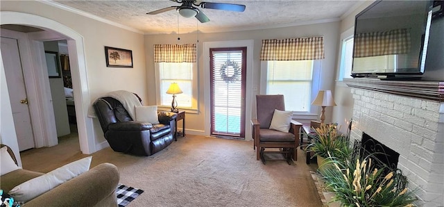 sitting room featuring light carpet, ceiling fan, a fireplace, a textured ceiling, and crown molding