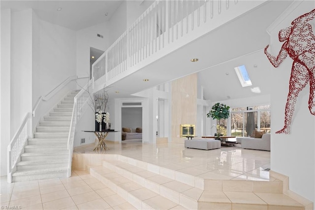 interior space with stairs, a skylight, and a towering ceiling