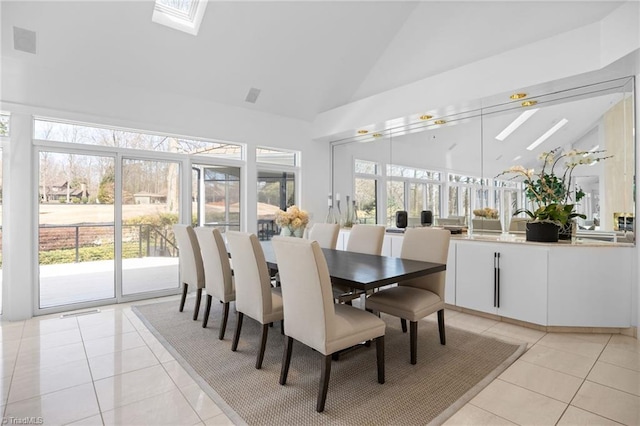 dining space with a healthy amount of sunlight, light tile patterned floors, a skylight, and high vaulted ceiling