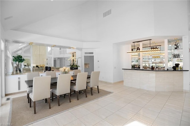 dining space featuring high vaulted ceiling, visible vents, and light tile patterned floors