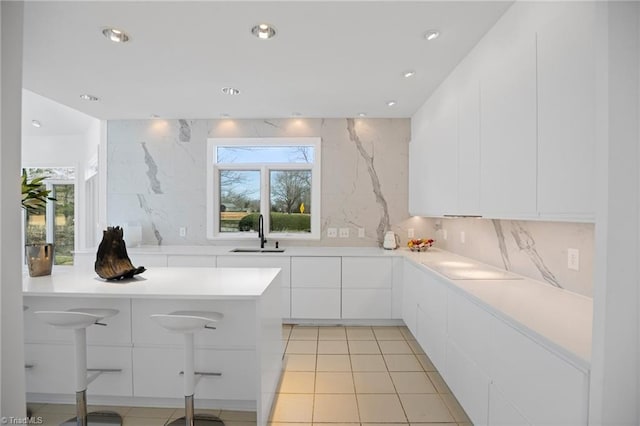 kitchen featuring recessed lighting, a sink, white cabinetry, light countertops, and modern cabinets