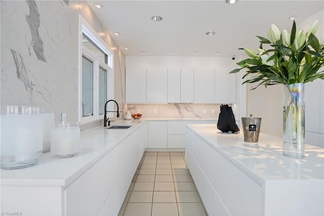 kitchen with a kitchen island, a sink, white cabinets, light countertops, and modern cabinets