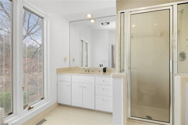 bathroom with visible vents, a shower stall, and vanity