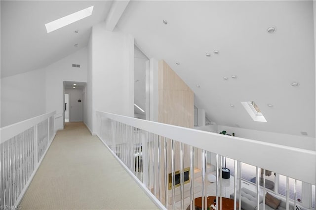 hallway featuring vaulted ceiling with skylight, visible vents, and light colored carpet