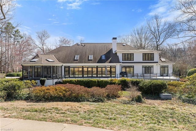 back of house featuring a sunroom and a chimney